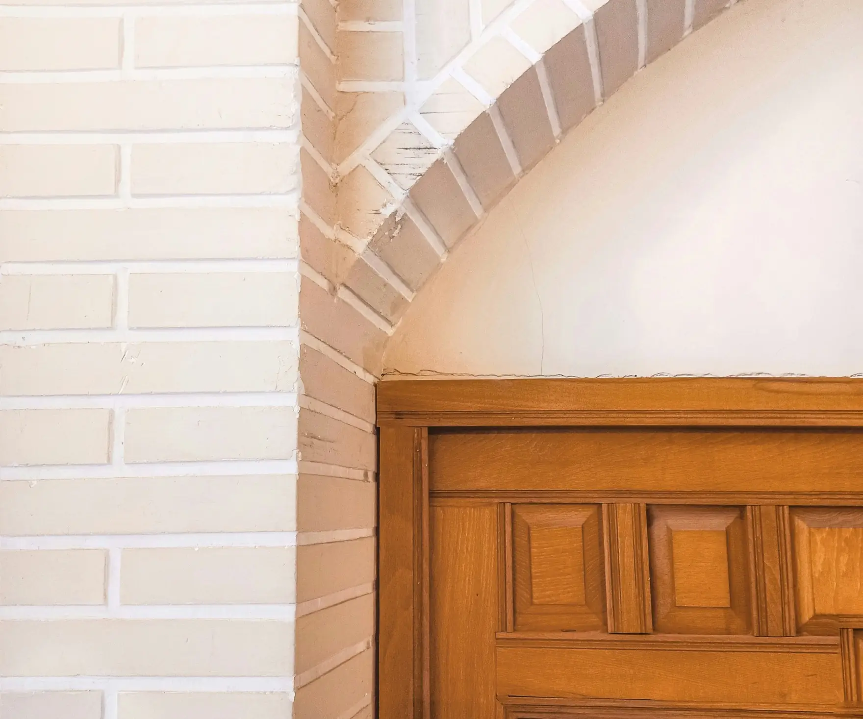 Arc de brique blanchie au-dessus d’une porte en chêne à panneaux